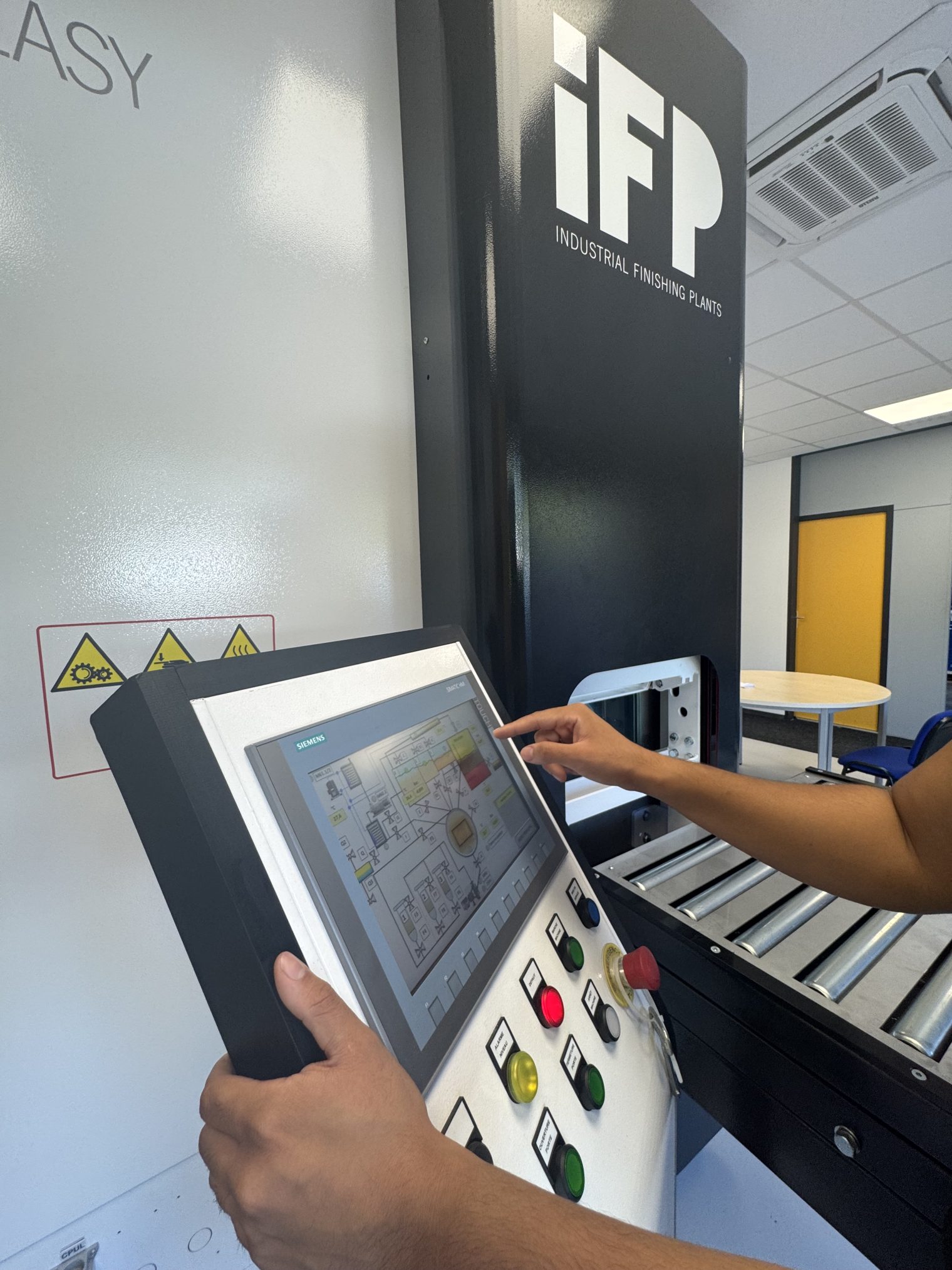 Mains d'un technicien sur l'écran de supervision Siemens d'une installation IFP EUROPE, pupitre à boutons lumineux